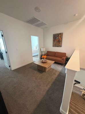 Ein geräumiges Wohnzimmer mit einem braunen Sofa, einem Couchtisch mit Blumenvase und einem Bild an der Wand.
