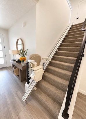 Eine Treppe mit Geländer, Teppichstufen und einem an der Wand befestigten Spiegel.