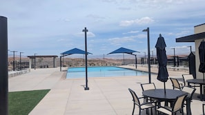 Área da piscina com vista clara para montanhas, assentos externos e guarda-sóis.