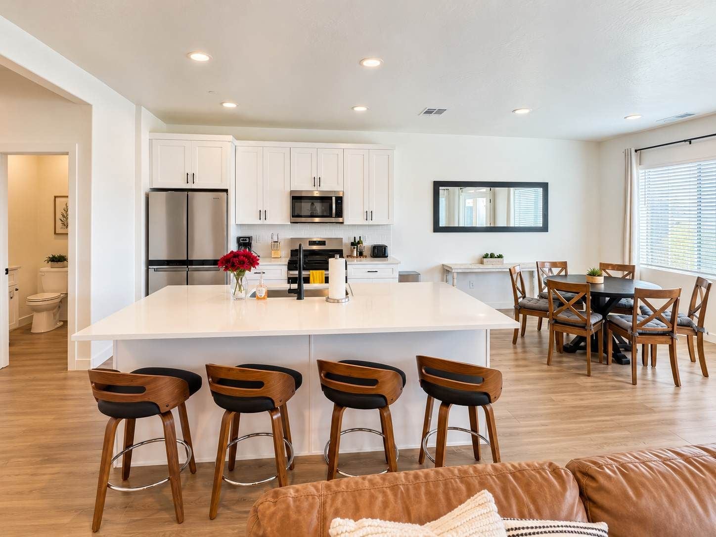 A modern kitchen with white cabinets, stainless steel appliances, and a central island with bar stools.