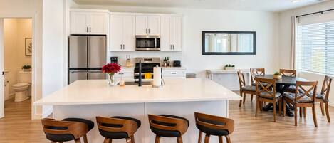 A modern kitchen with white cabinets, stainless steel appliances, and a central island with bar stools.