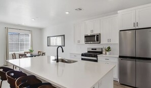 A modern kitchen with white cabinetry, a stainless steel refrigerator, a built-in oven, and a microwave. - Long Valley Family Retreat - Sleeps 8 (Washington)