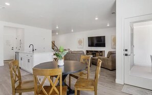 A modern living room with a round dining table, sofas, and a TV. - Long Valley Family Retreat - Sleeps 8 (Washington)