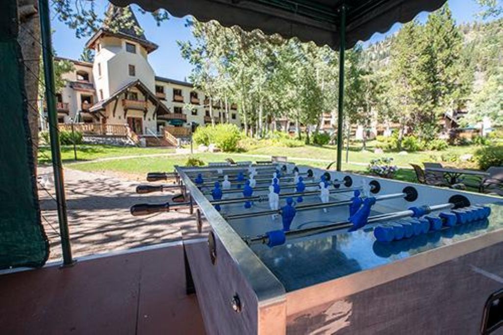 A foosball table under a covered area with a building in the background.