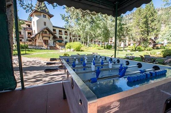 A foosball table under a covered area with a building in the background.