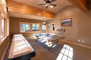 Une pièce avec une table de ping-pong, un plafond en bois et des fenêtres.