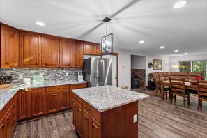 Una cocina moderna con armarios de madera, encimeras de granito y un refrigerador de acero inoxidable.