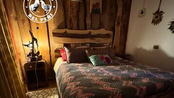Une chambre confortable avec un lit en bois, une table de chevet et une lampe fixée au mur.