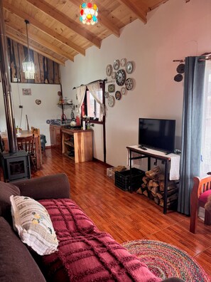 A cozy living room with a TV, wooden furniture, a fireplace, and a dining area.