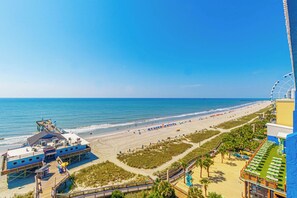 A beachside view with a pier, beach umbrellas, and a boardwalk. - Oceanfront 1BR Condo at Yachtsman Resort S801 (Myrtle Beach)