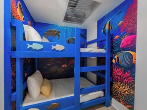 Une chambre avec des lits superposés, dont un des murs est décoré d’une fresque représentant un paysage sous-marin.