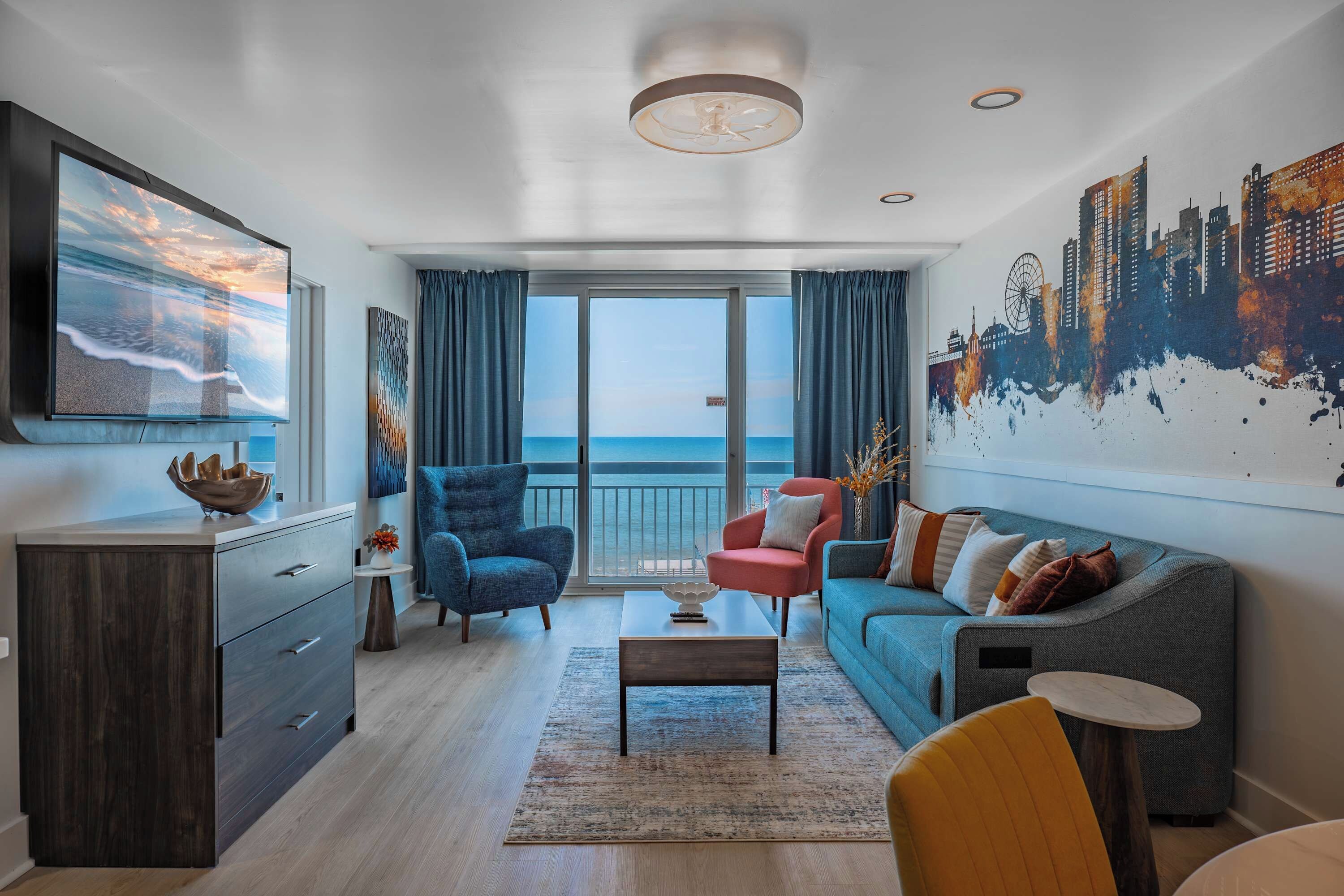 Una sala de estar moderna con un gran ventanal, un mural con vista a la ciudad, un sofá, una silla y un televisor.