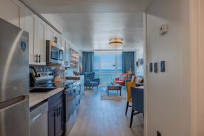 A modern kitchen with stainless steel appliances, a dining area with a view, and a living room with a balcony. - Oceanfront 1BR Condo at Yachtsman Resort S801 (Myrtle Beach)