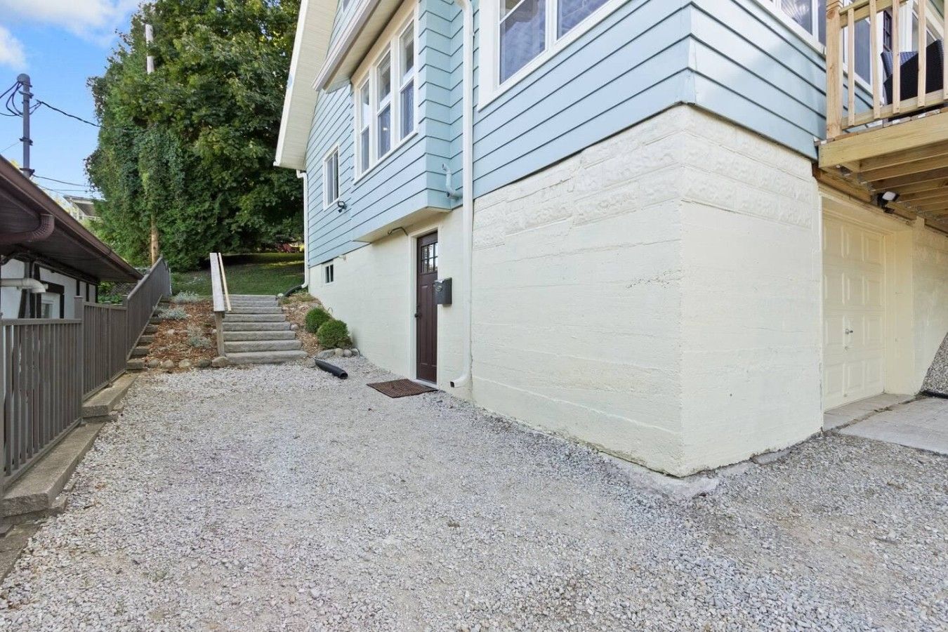 A two-story house with a gravel driveway and a wooden deck.