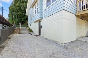 A two-story house with a gravel driveway and a wooden deck.