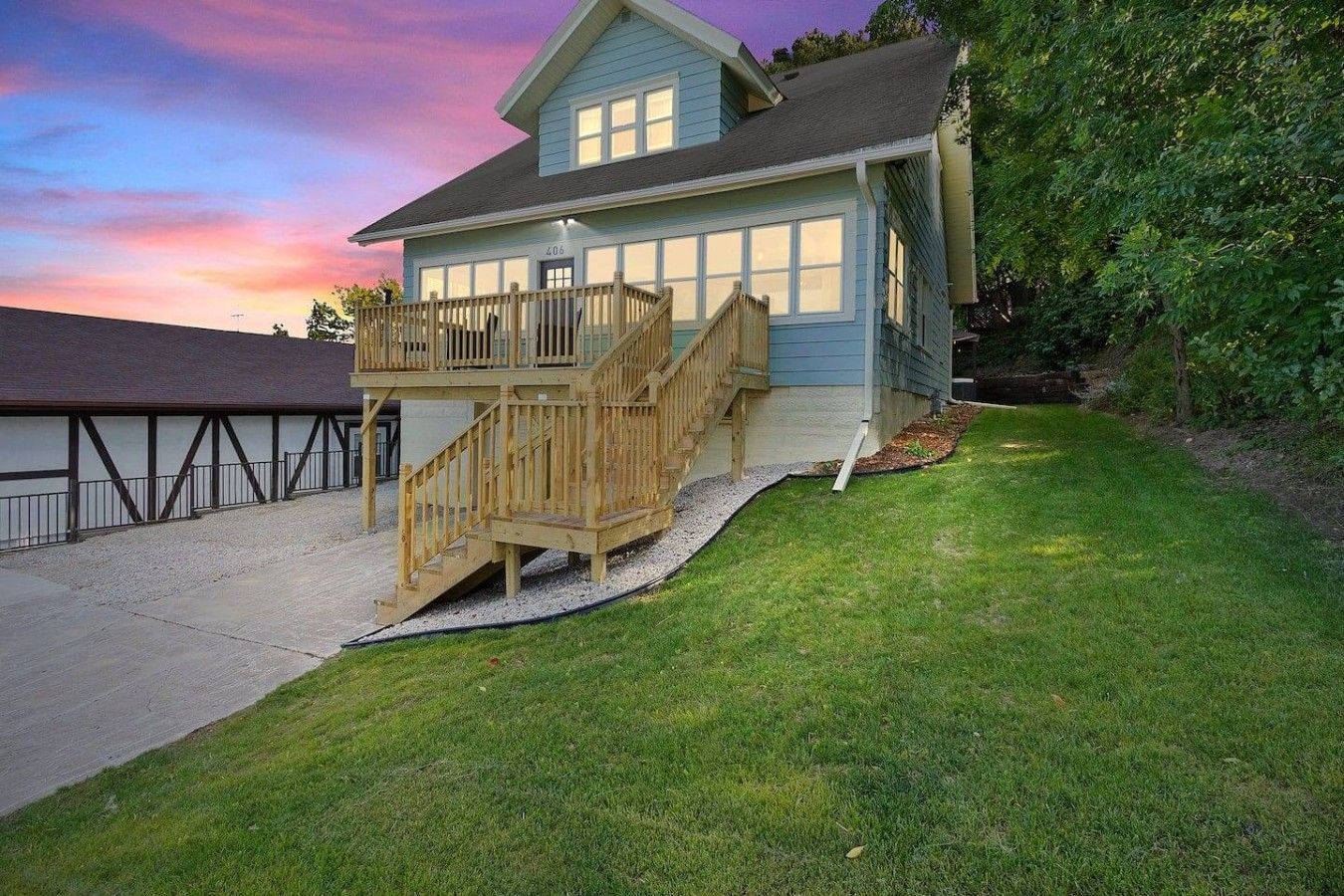 A two-story house with a wooden deck and a staircase leading to the second floor.