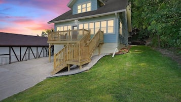A two-story house with a wooden deck and a staircase leading to the second floor.