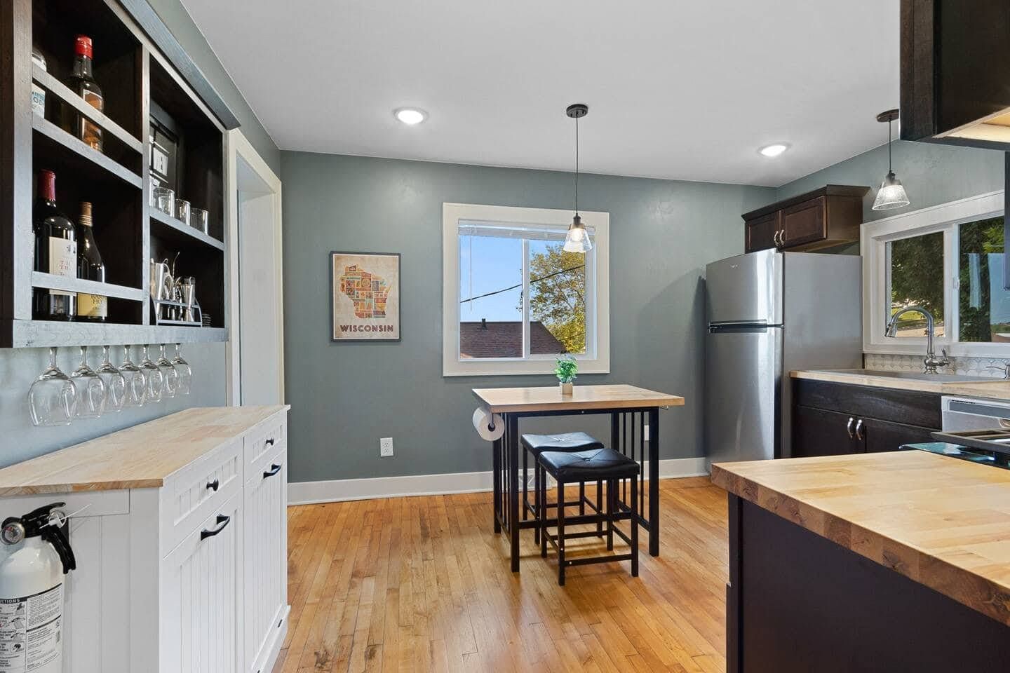 A modern kitchen with a wooden countertop, a built-in wine rack, and a stainless steel refrigerator.