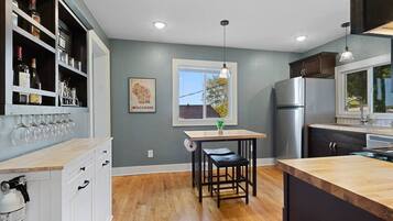 A modern kitchen with a wooden countertop, a built-in wine rack, and a stainless steel refrigerator.