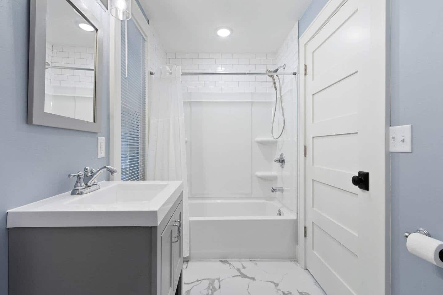 A bathroom with a white sink, mirror, and shower area.