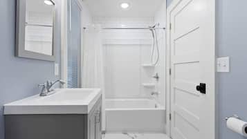 A bathroom with a white sink, mirror, and shower area.