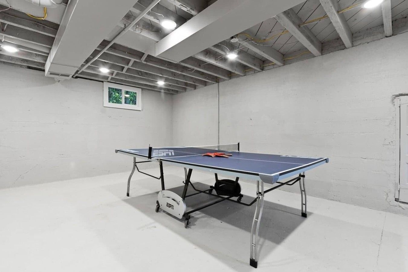 Ett bordtennisbord i ett rum med vita väggar och ett betonggolv.