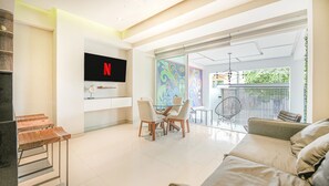 Una sala de estar moderna con televisor, comedor y balcón con vistas.