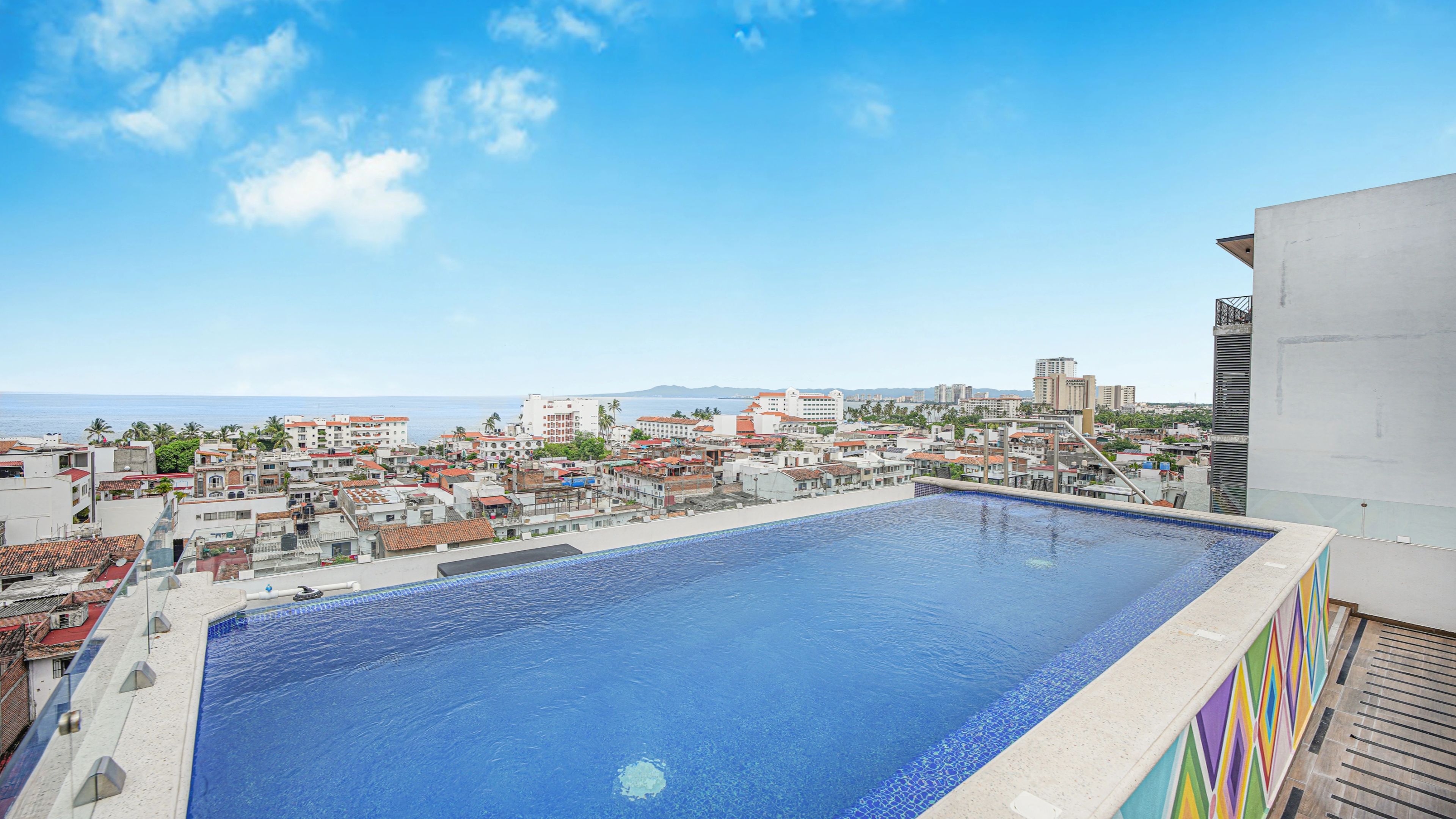 Piscina en la azotea con vistas a la ciudad, rodeada de edificios.