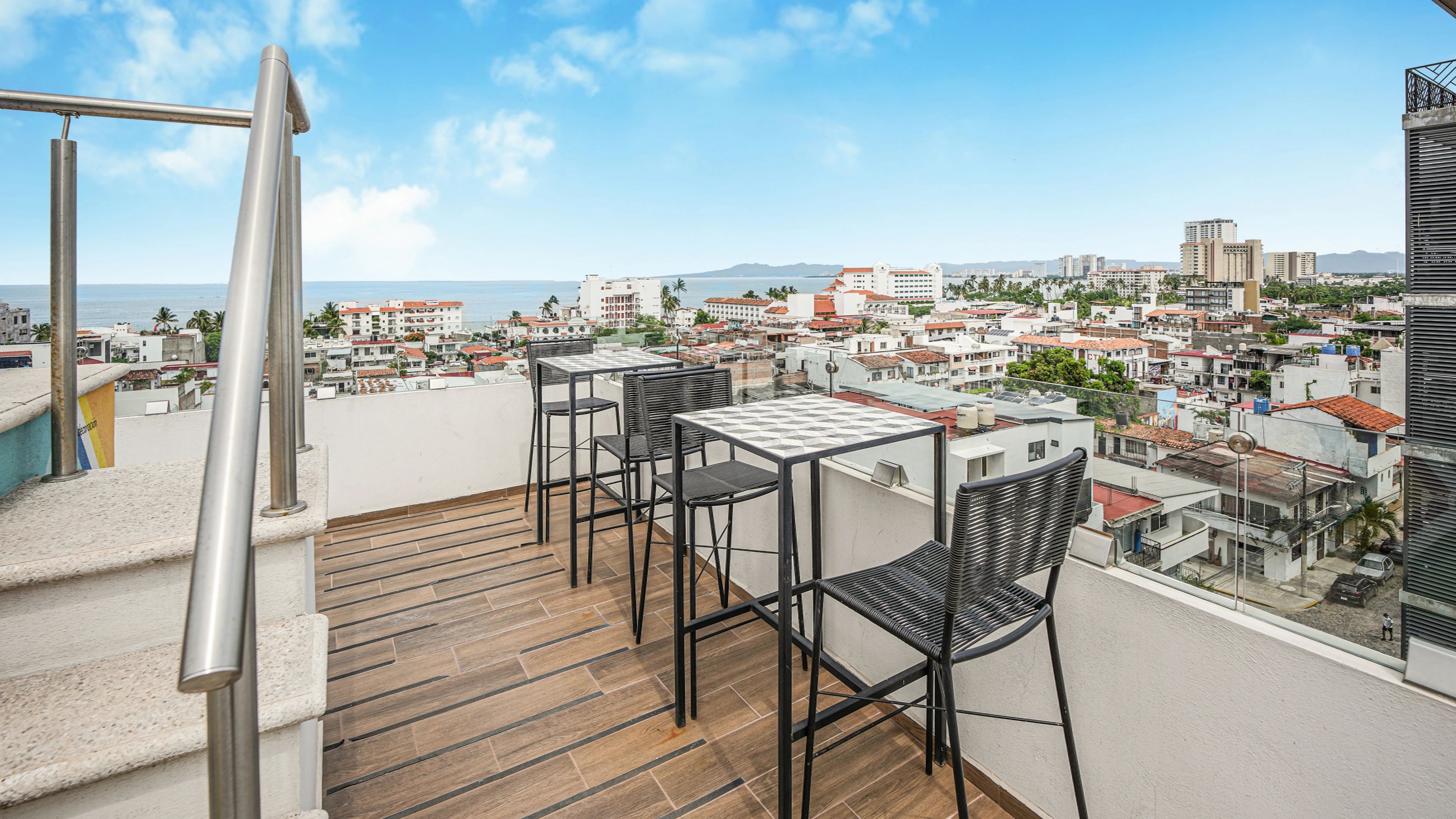 Terraza en la azotea con vistas a una ciudad costera, que incluye una mesa y sillas.