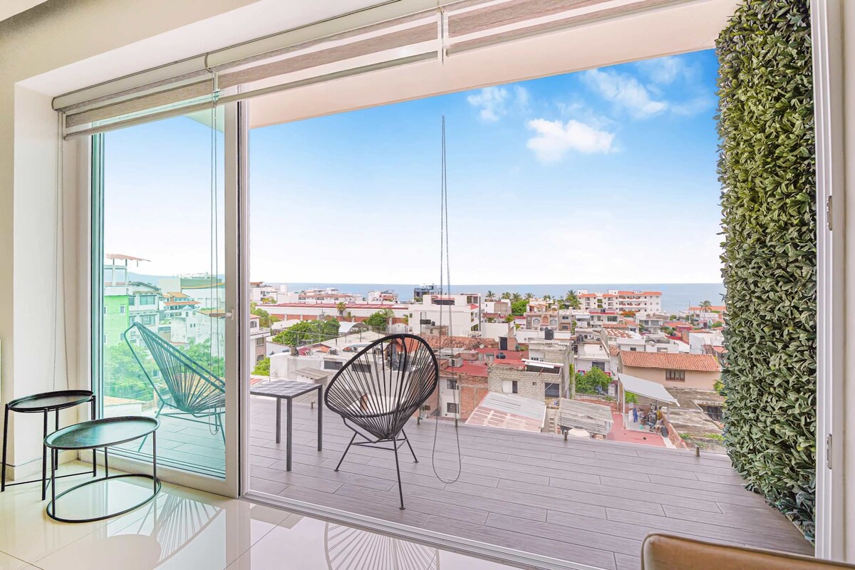 A balcony with a city view, a chair, and a table.