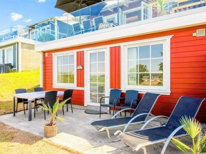Ein rotes Gebäude mit Balkon, Außenbestuhlung und freiem Blick auf die umliegende Landschaft.