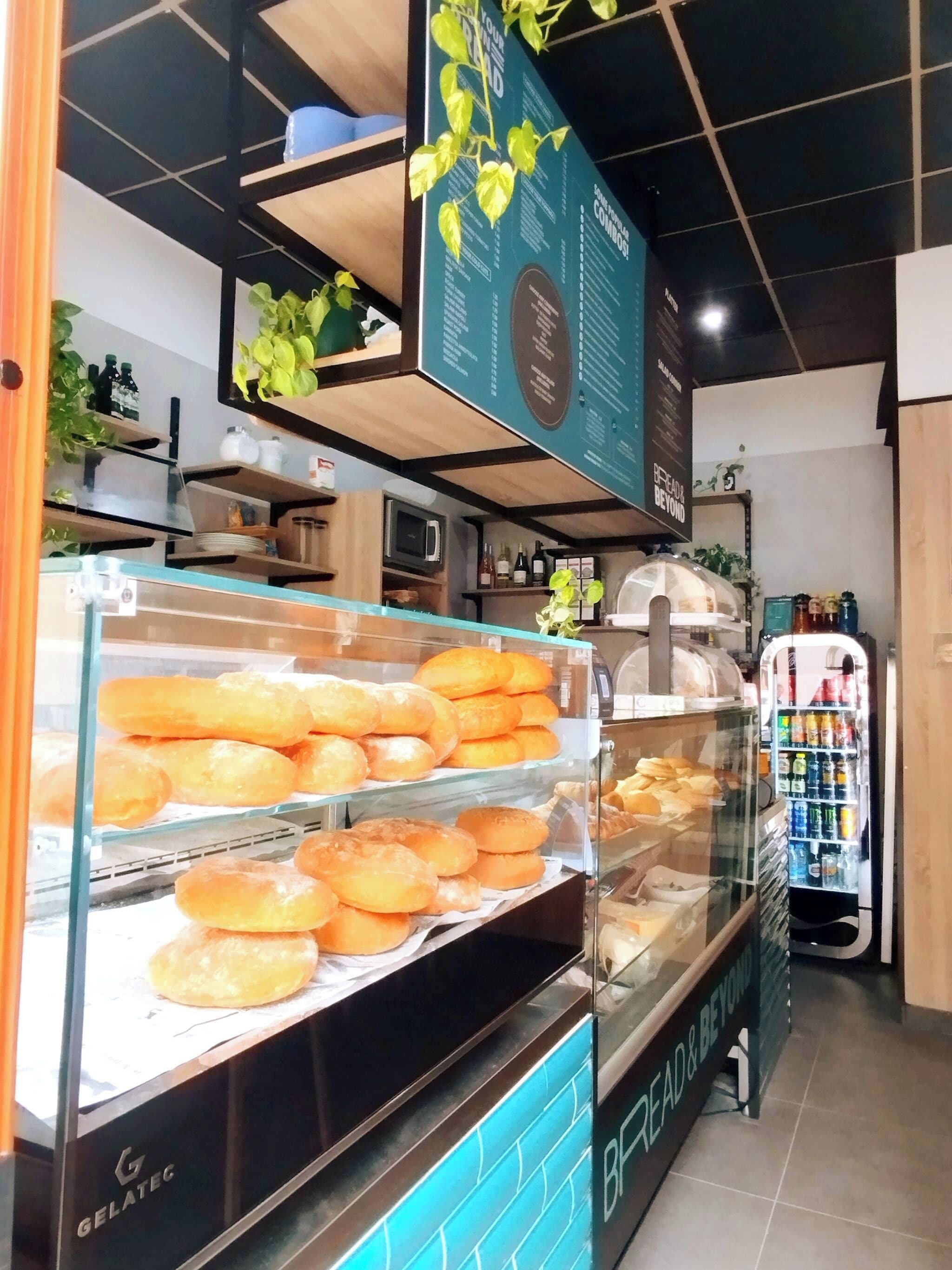 Een bakkerijdisplay met diverse gebakjes, een drankdispenser en een bord met een slogan.