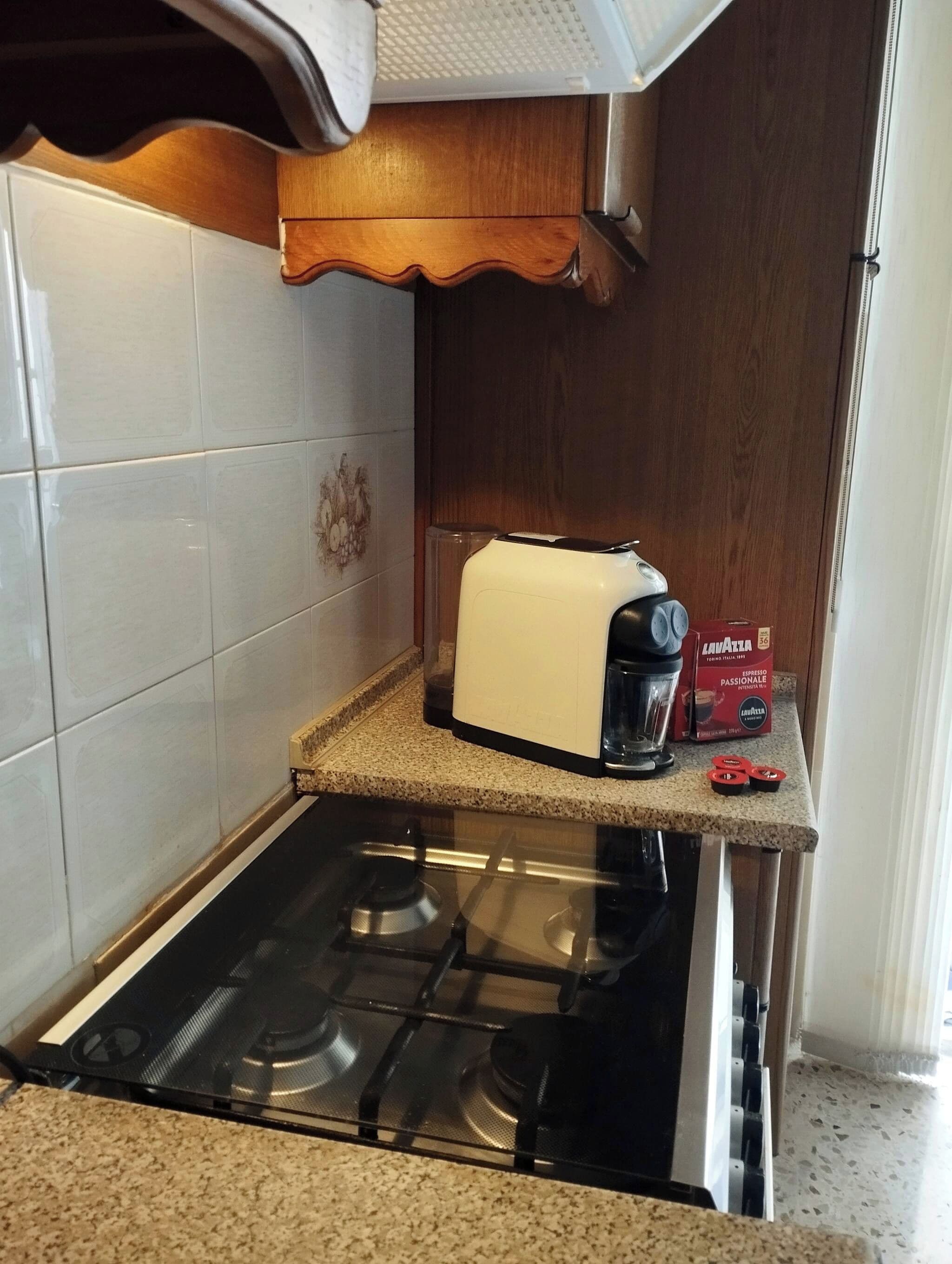 Une cuisine équipée d’une cuisinière à gaz, d’un grille-pain et d’une machine à café, le tout posé sur le plan de travail.