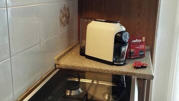 Une cuisine équipée d’une cuisinière à gaz, d’un grille-pain et d’une machine à café, le tout posé sur le plan de travail.