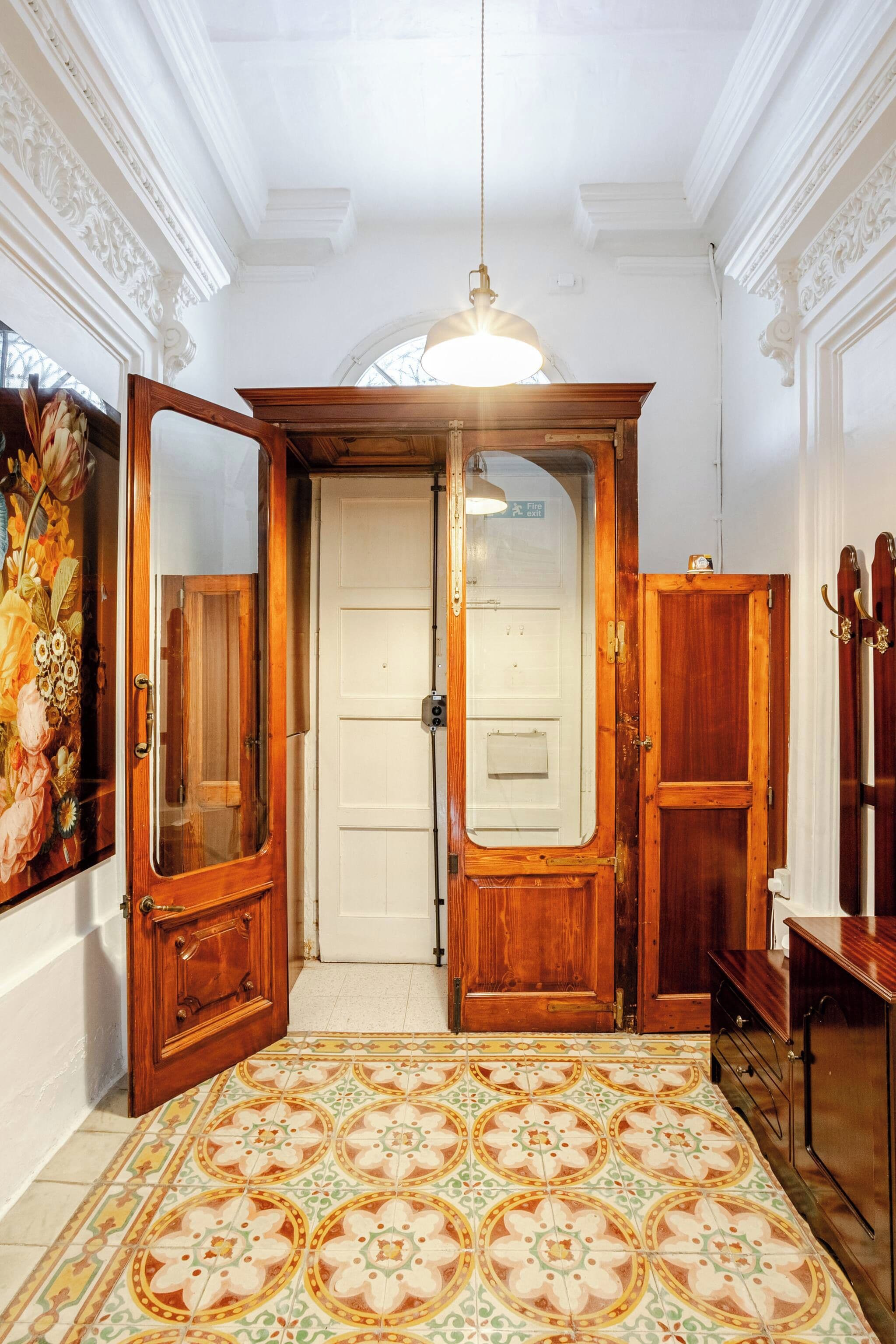 Una habitación con suelo estampado, una puerta blanca y una lámpara colgante.