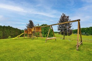 Un tobogan de fusta i una caseta d'arbòria en un camp de gespa.