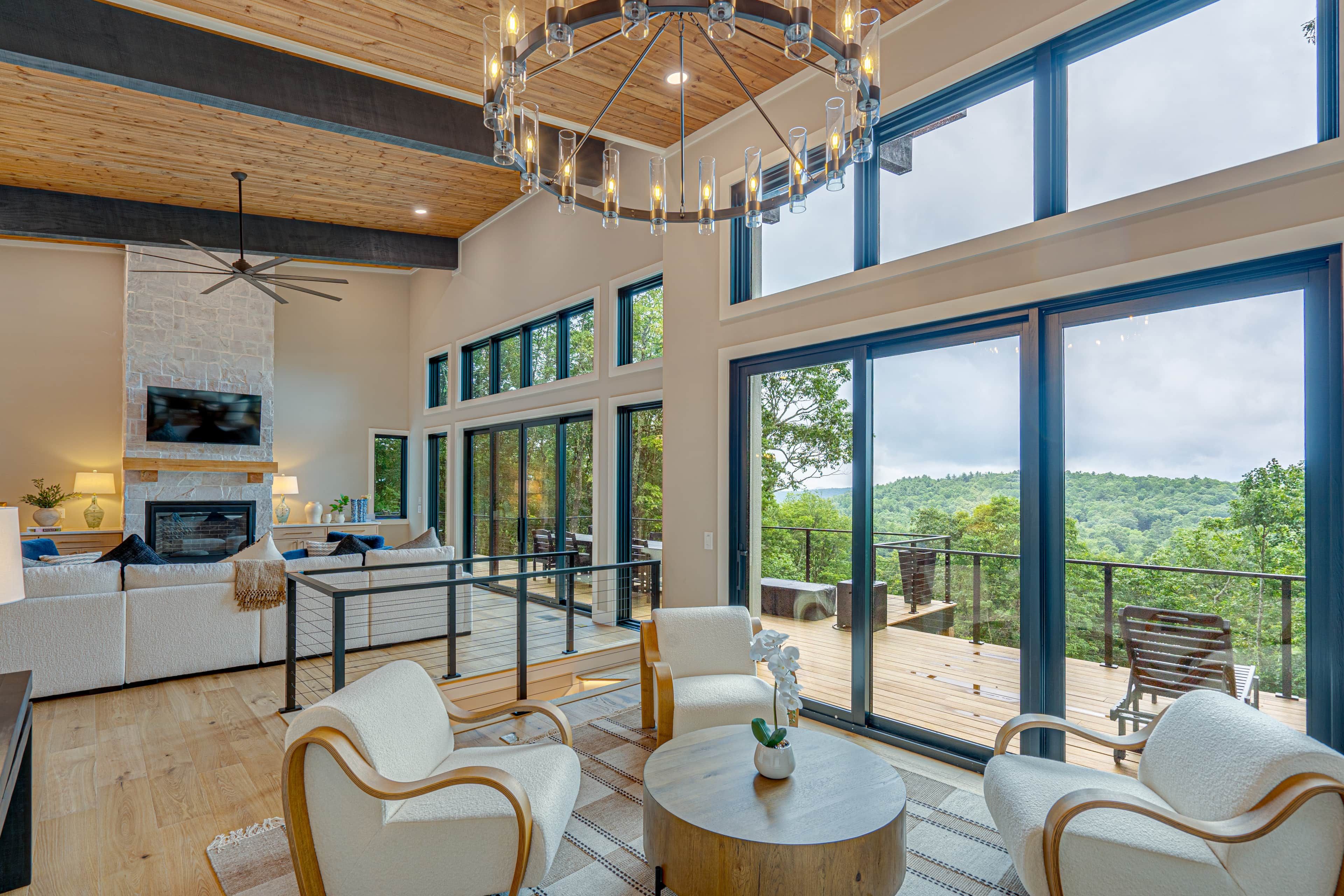 A spacious living area with a fireplace, comfortable seating, and large windows offering a view of the outdoors.