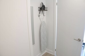 Ein Flur mit einer weißen Tür, einem Kleiderständer mit einem gemusterten Kleidungsstück und einem Lichtschalter an der Wand.