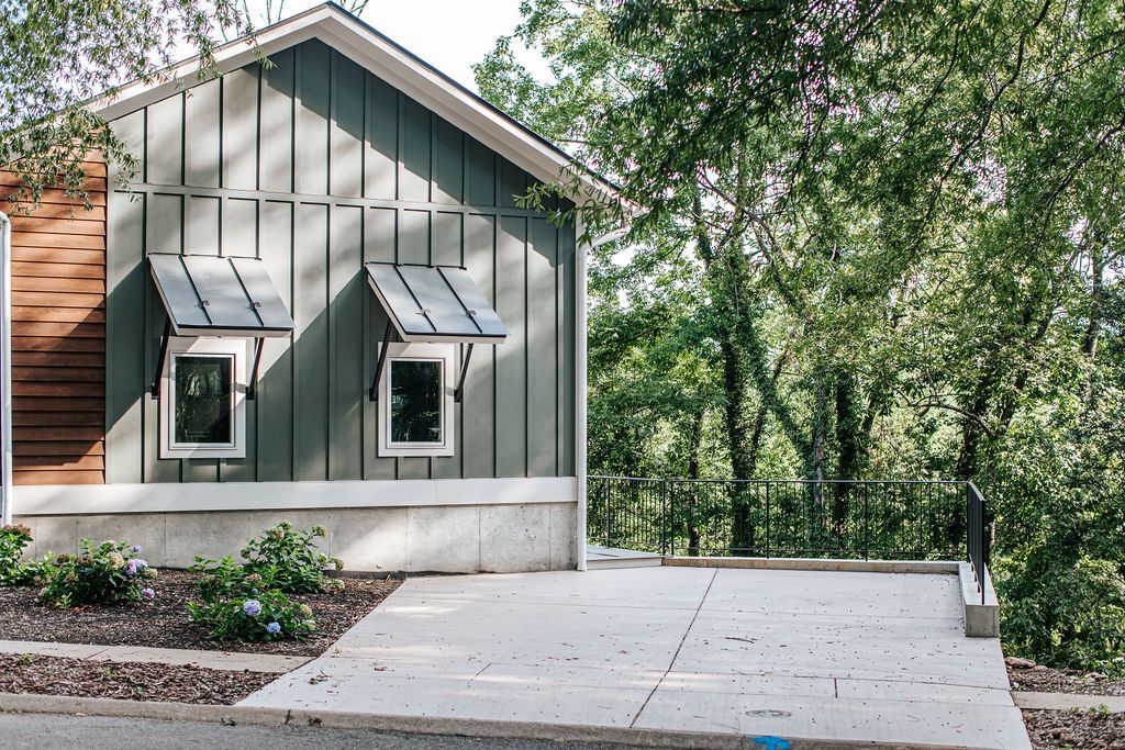 Un bâtiment moderne doté d’un toit en pente, de deux fenêtres et d’une terrasse en béton.