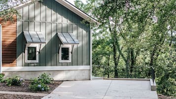 Un bâtiment moderne doté d’un toit en pente, de deux fenêtres et d’une terrasse en béton.