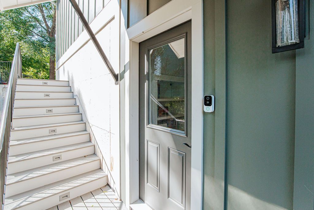 A staircase leading to a door with a window, a mailbox, and a wall-mounted light fixture.
