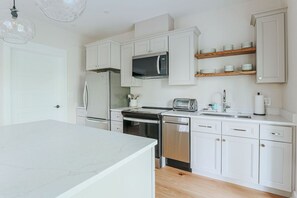 A modern kitchen with white cabinetry, a microwave, a toaster, and a dishwasher.