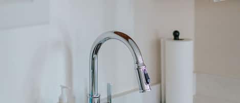 A bathroom with a white sink, a chrome faucet, a soap dispenser, and a toilet paper holder.