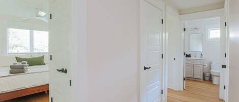 A bedroom with a bed, a window, and a door leading to a bathroom.