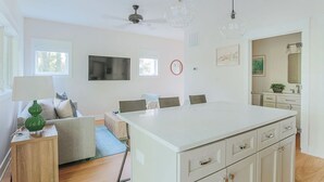 A modern kitchen with white cabinets, a central island, and pendant lighting. - Riverbluff Nest (Charlottesville)