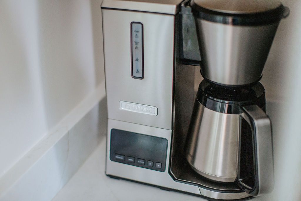 Una cafetera con pantalla digital y bandeja de goteo de acero inoxidable.