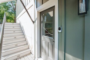 A staircase leading to a door with a window, a mailbox, and a wall-mounted light fixture. - Riverbluff Nest (Charlottesville)