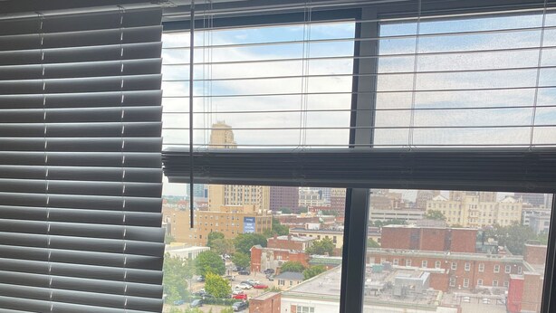 Ein Zimmer mit großem Fenster und Blick auf eine Stadtlandschaft.