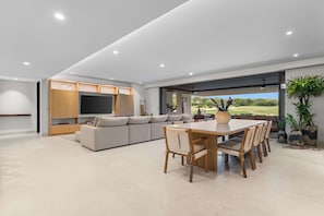 A modern living space with a dining area, a sofa, and a TV. - Casa Lua: Golf Views & Breakfast Prep in Punta Mita (Desarrollo Punta Mita)