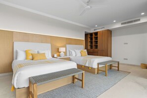 A modern bedroom with two beds, a wooden wardrobe, a ceiling fan, and a small table. - Casa Lua: Golf Views & Breakfast Prep in Punta Mita (Desarrollo Punta Mita)